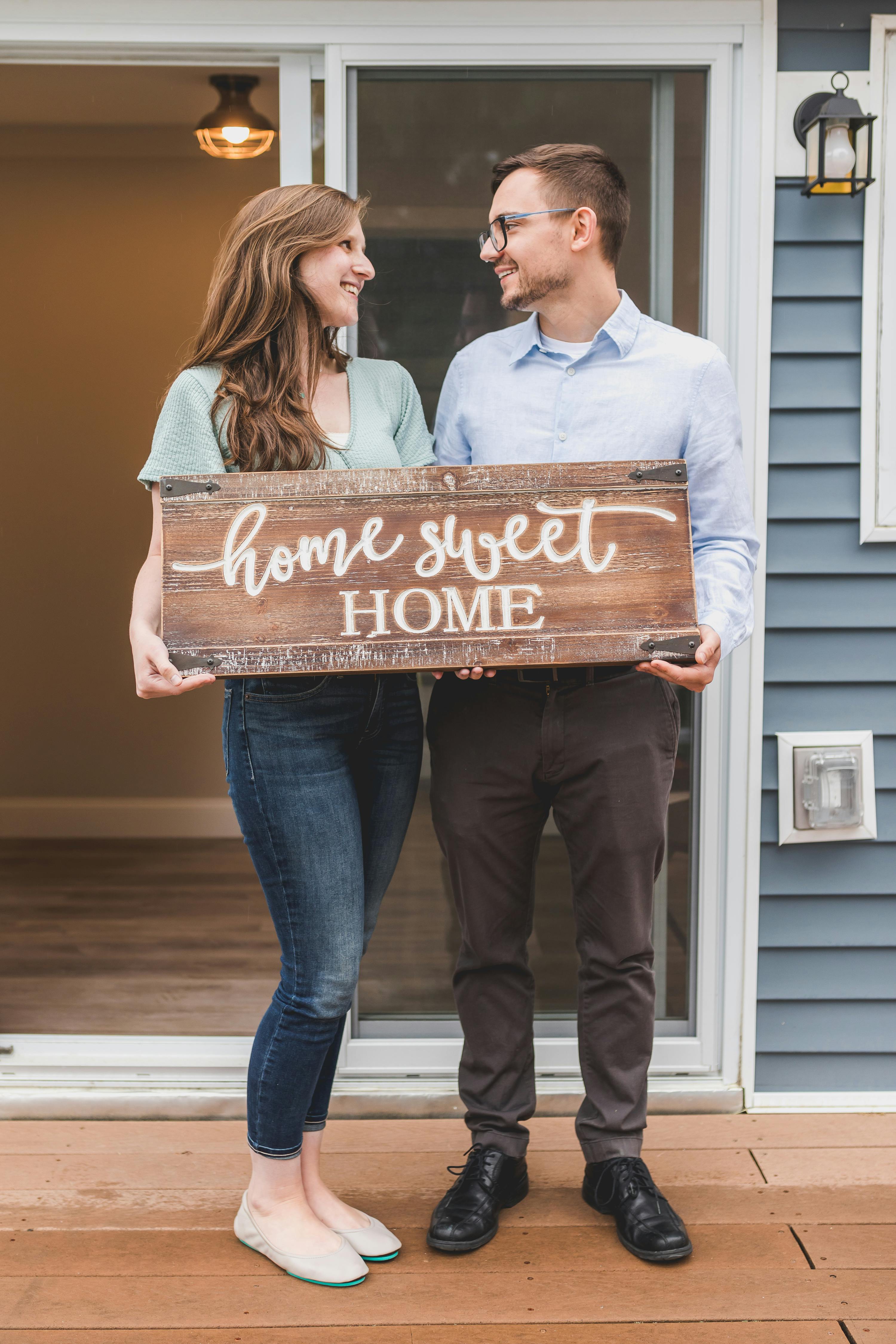 Photo by RDNE Stock project: https://www.pexels.com/photo/happy-couple-standing-face-to-face-and-holding-a-home-sweet-home-wooden-signage-8293704/